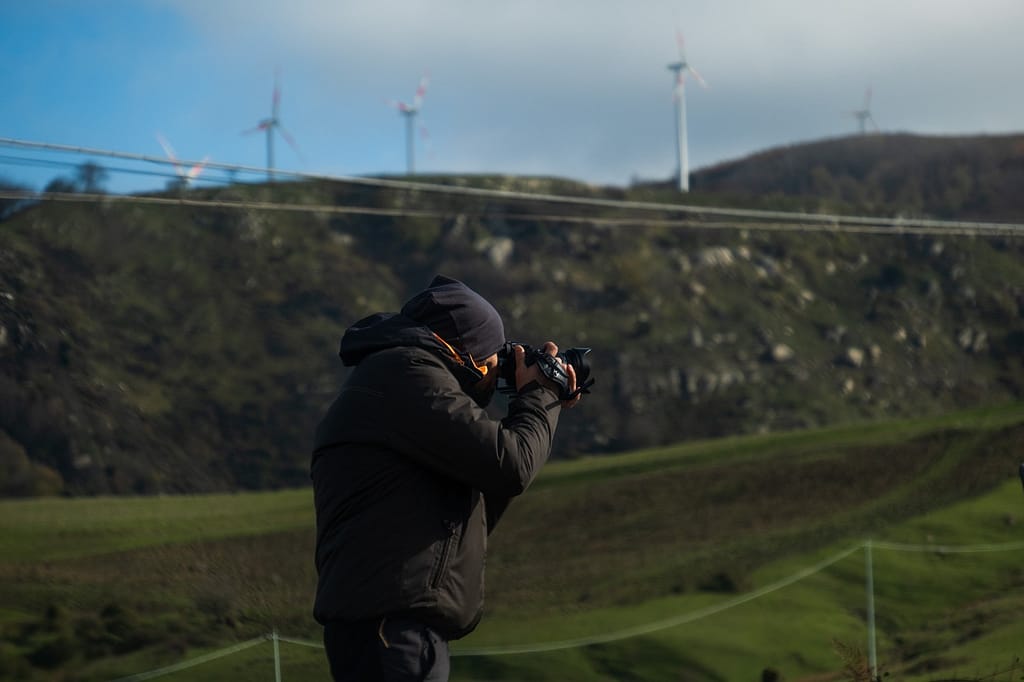 Daniele Tranchita fotografa un paesaggio di colline verdi con pale eoliche sullo sfondo. La foto con la X100VI resta per un altro articolo.