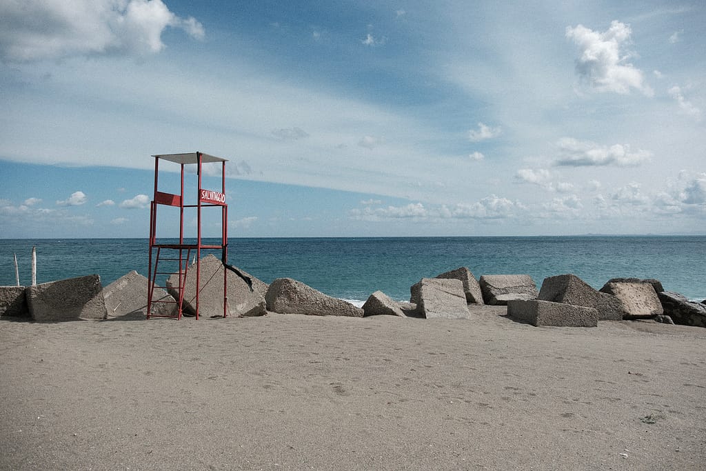 Torretta rossa di salvataggio vuota tra blocchi di cemento sulla spiaggia