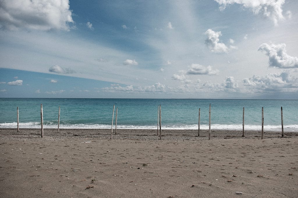 Pali di legno piantati sulla spiaggia vuota davanti al mare