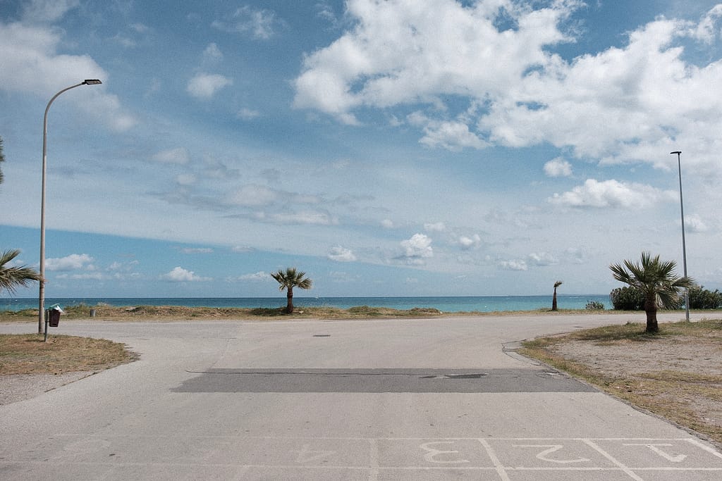 Gioco della campana disegnato sull’asfalto, con palme e lampioni davanti al mare