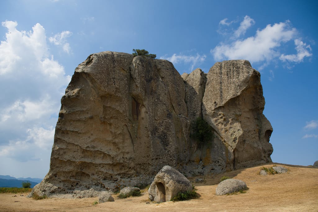 Grande megalite dell'Argimusco su un prato secco sotto il cielo blu