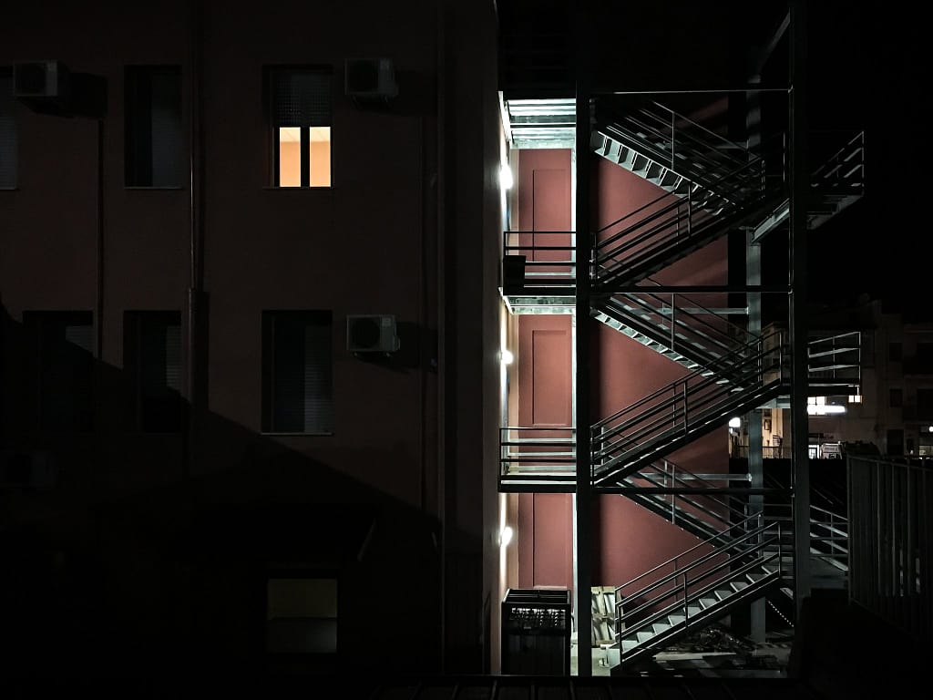 Scala antincendio in metallo illuminata di notte su una facciata, Sant'Agata di Militello