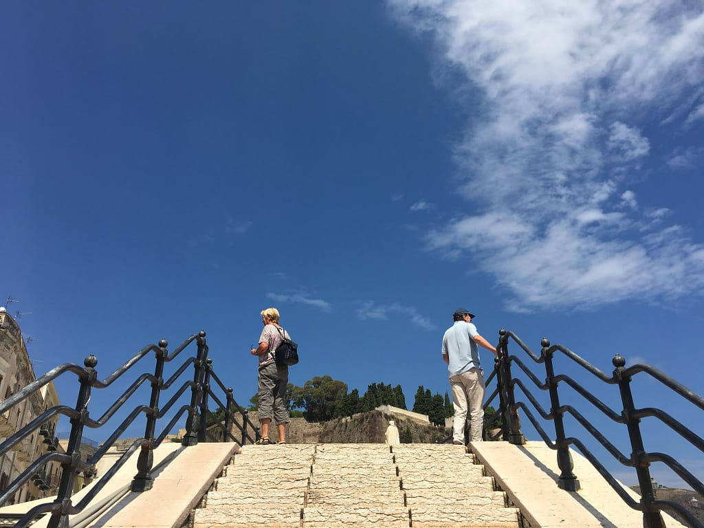 Due persone in cima a una scalinata con ringhiere sotto un cielo blu, Lipari