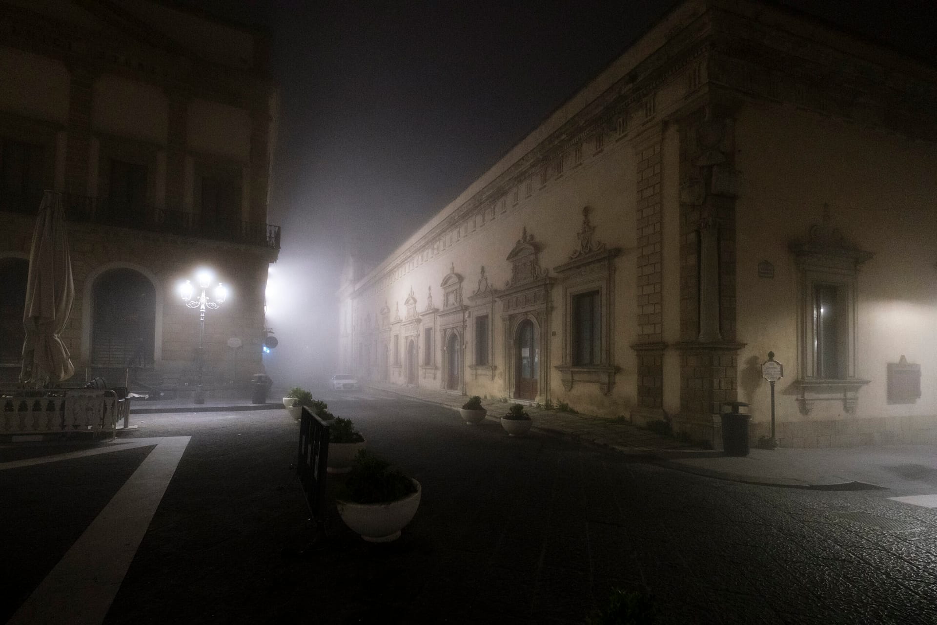 Un palazzo storico di Caltagirone nella nebbia, di notte, illuminato da un lampione