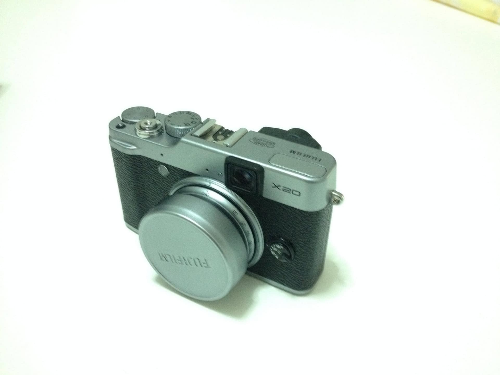 La Fujifilm X20 silver con il tappo dell’obiettivo, su un tavolo bianco