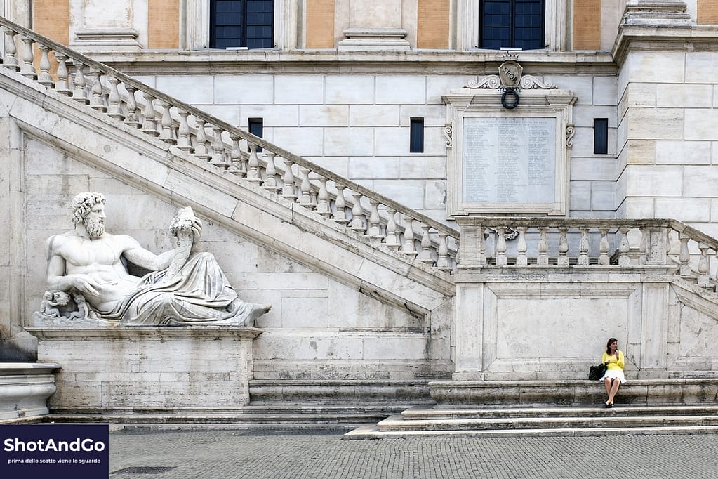 Composizione fotografica: poche regole che fanno davvero la differenza Donna seduta su una scalinata monumentale accanto a una statua, esempio di composizione fotografica con equilibrio tra soggetto e architettura.