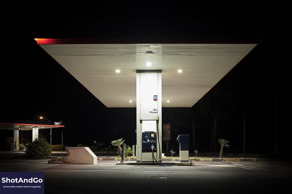 Stazione di servizio illuminata nella notte, fotografata con una composizione essenziale e simmetrica.