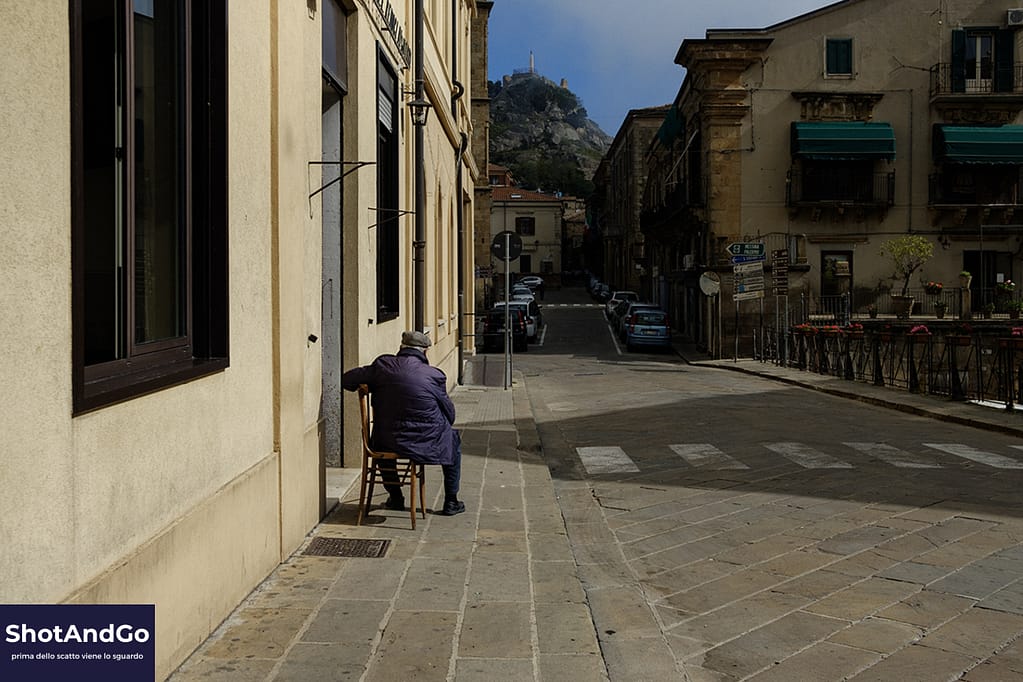 Fotografia e solitudine: perché scattiamo quando nessuno guarda Persona seduta da sola sul marciapiede di una strada cittadina, scena che richiama il tema della solitudine e dell’osservazione nella fotografia.