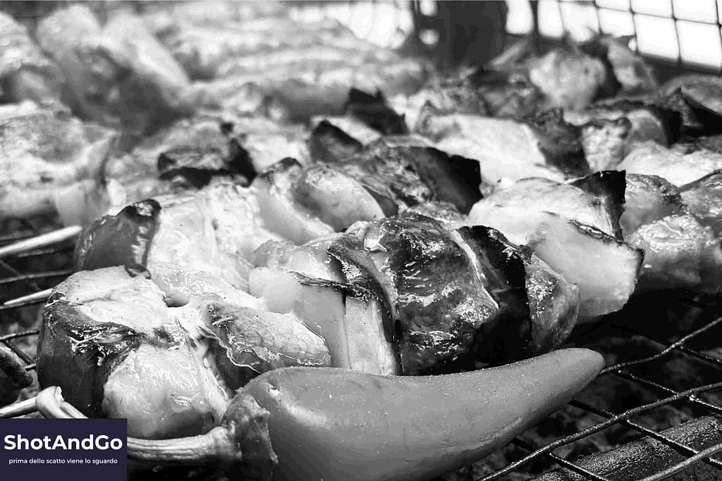 Fotografia in bianco e nero di pesce su una griglia, con forte contrasto e ricche texture, utilizzata per mostrare l’importanza di luce e materia nella fotografia monocromatica.