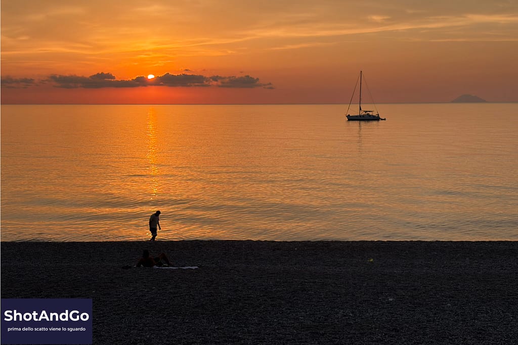 Persona che osserva il mare al tramonto fotografata con uno smartphone: la qualità nasce dallo sguardo, non dalle impostazioni.